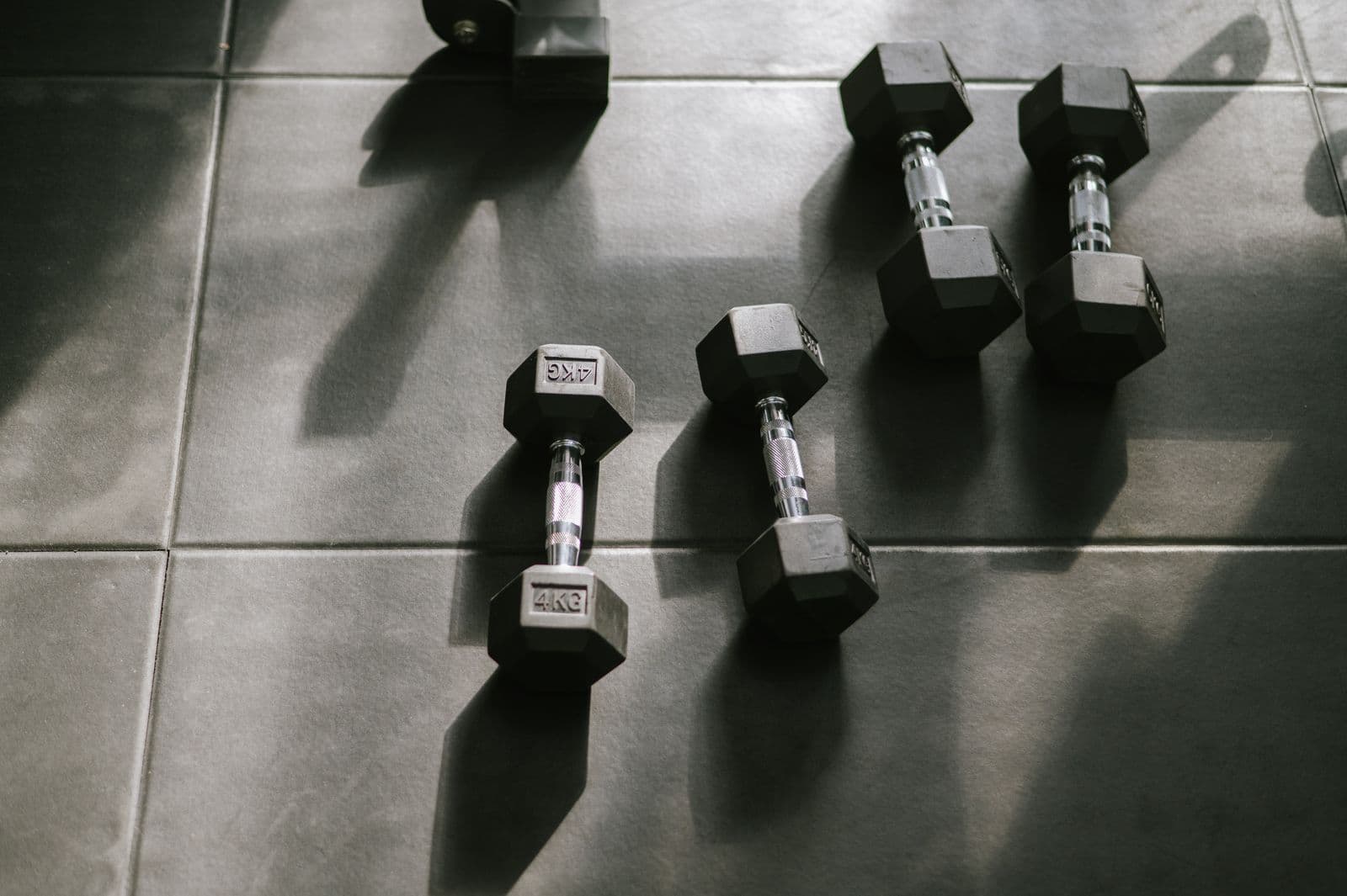 Hex dumbbells laid out on a gym floor in low afternoon light