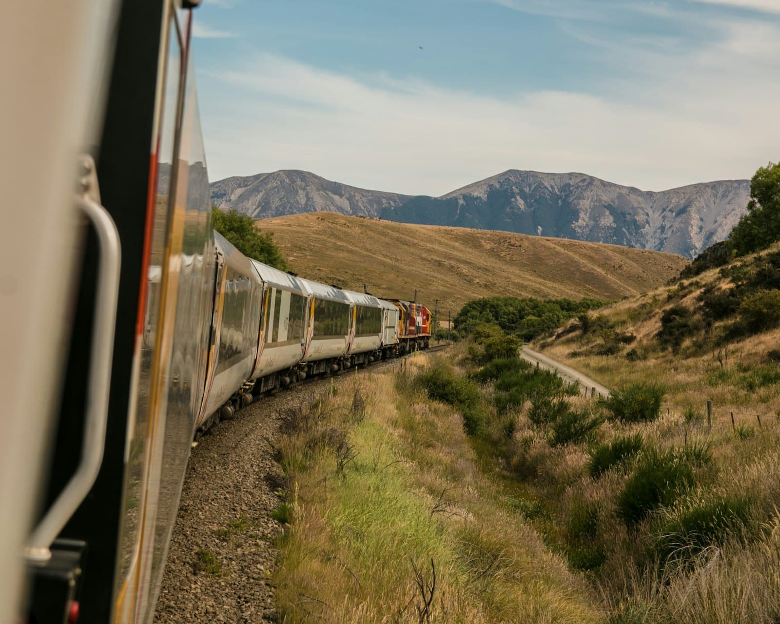 A train curving through a valley towards distant mountains