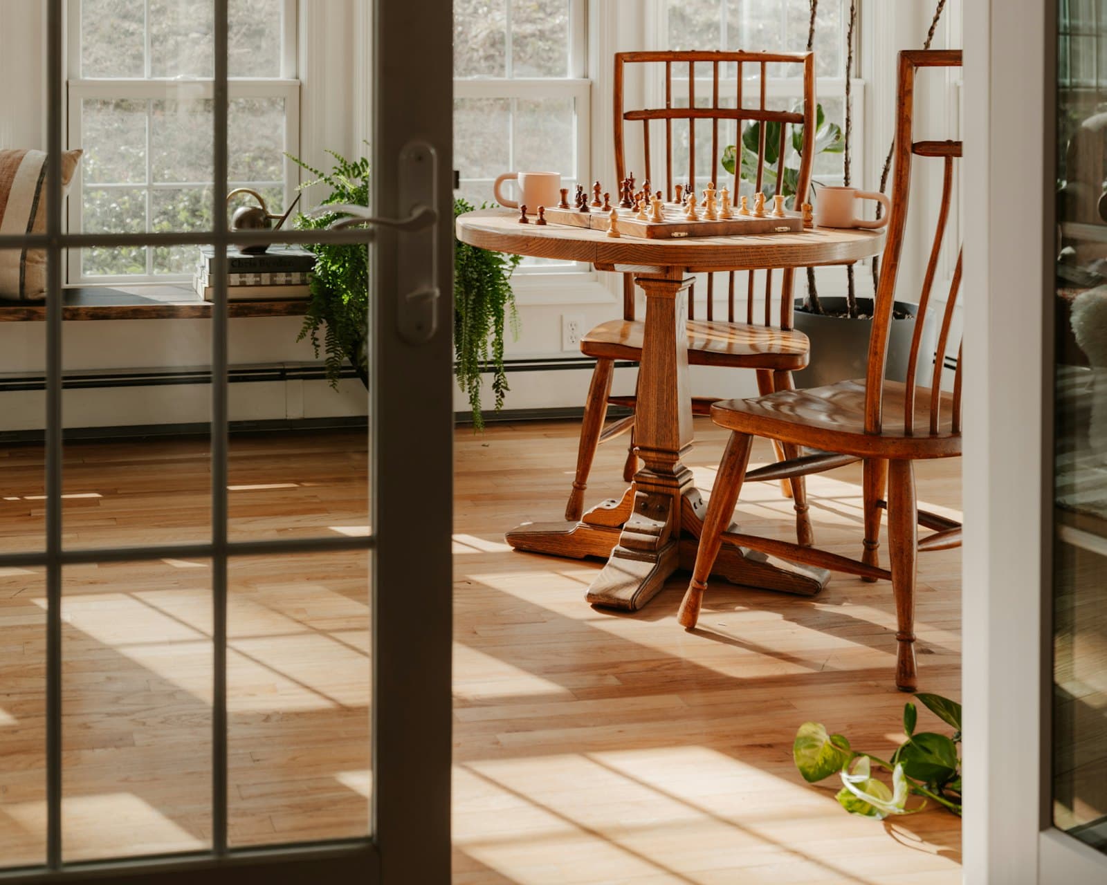 A sunlit corner table with two mugs and a half-played chess set