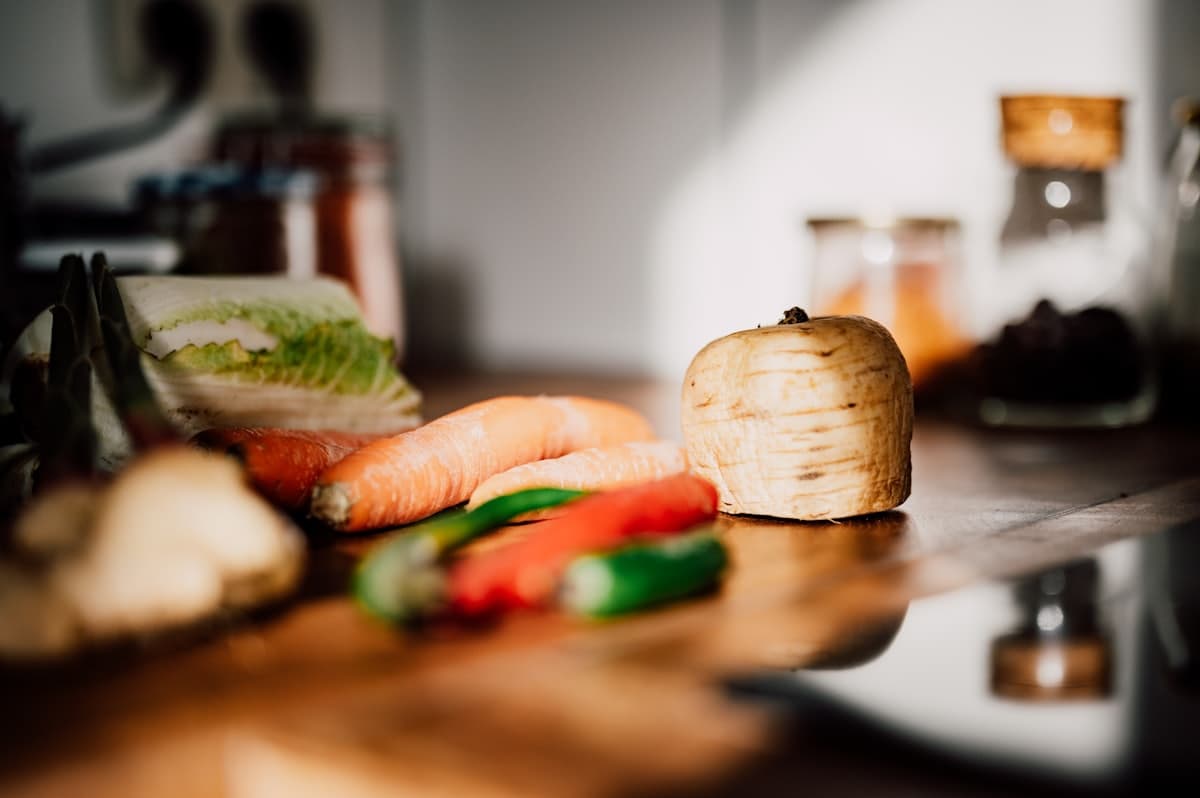 Fresh vegetables laid out on a warm wooden kitchen counter